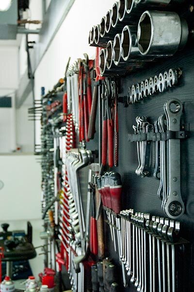 Das Bild zeigt eine Werkstattwand mit zahlreichen Handwerkzeugen wie Schraubenschlüsseln, Zangen, Ratschen und Stecknüssen, ordentlich sortiert und