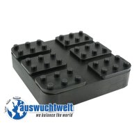 Das Bild zeigt ein schwarzes, quadratisches Kunststoffstück mit einer Höhe von einigen Zentimetern. Auf der Oberseite sind sechs rechteckige vertiefte Bereiche angeordnet, die wie kleine Plattformen aussehen. Jeder dieser Bereiche hat mehrere kleine, zylindrische Erhebungen, ähnlich wie bei einem Legostein. Unten links im Bild befindet sich ein Logo mit einer stilisierten Weltkugel und dem Text „auswuchtwelt“ sowie dem Slogan „we balance the world“. Das Kunststoffstück könnte ein technisches Zubehörteil oder eine Vorrichtung zur Lagerung oder Fixierung sein.