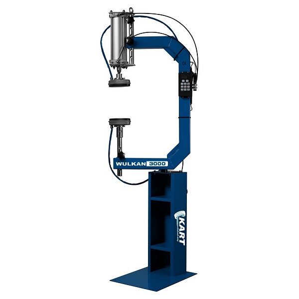 Das Bild zeigt eine große, freistehende, blaue Industrie-Maschine mit der Aufschrift Wulkan 3000 und dem Herstellernamen Kart. Die Maschine hat einen C-förmigen Rahmen, an dessen oberem Arm sich ein zylinderförmiges Gerät mit Kabeln und Schläuchen befindet. In der Mitte des Rahmens sind zwei gegenüberliegende runde Werkzeuge angebracht. Auf der rechten Seite des oberen Arms ist ein schwarzes Bedienfeld mit Tasten angebracht. Die Maschine steht stabil auf einem rechteckigen Fuß.