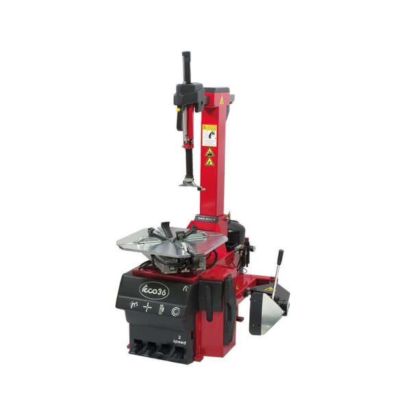 Das Bild zeigt eine rote, moderne Reifenmontiermaschine mit schwarzem Bedienelement im unteren Bereich, einem Drehteller zum Einspannen von Reifen, einem senkrechten Arm mit Montierkopf und mehreren Hebeln sowie Warnhinweisen auf der Maschine.