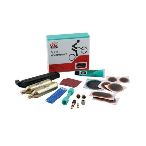 Das Bild zeigt ein Fahrrad-Reparaturset für Mountainbikes mit verschiedenen Komponenten: einer Schachtel mit der Aufschrift REMA TIP TOP TT 06 MOUNTAINBIKE und einer stilisierten Zeichnung eines Fahrrads, zwei Reifenheber, zwei CO2-Kartuschen, ein Stück Schleifpapier, mehrere selbstklebende Flicken in unterschiedlichen Größen und Formen, ein grünes Werkzeug, ein blaues Gitterwerkzeug, Ventiladapter, eine Tube Vulkanisierlösung und weiteres kleines Zubehör.